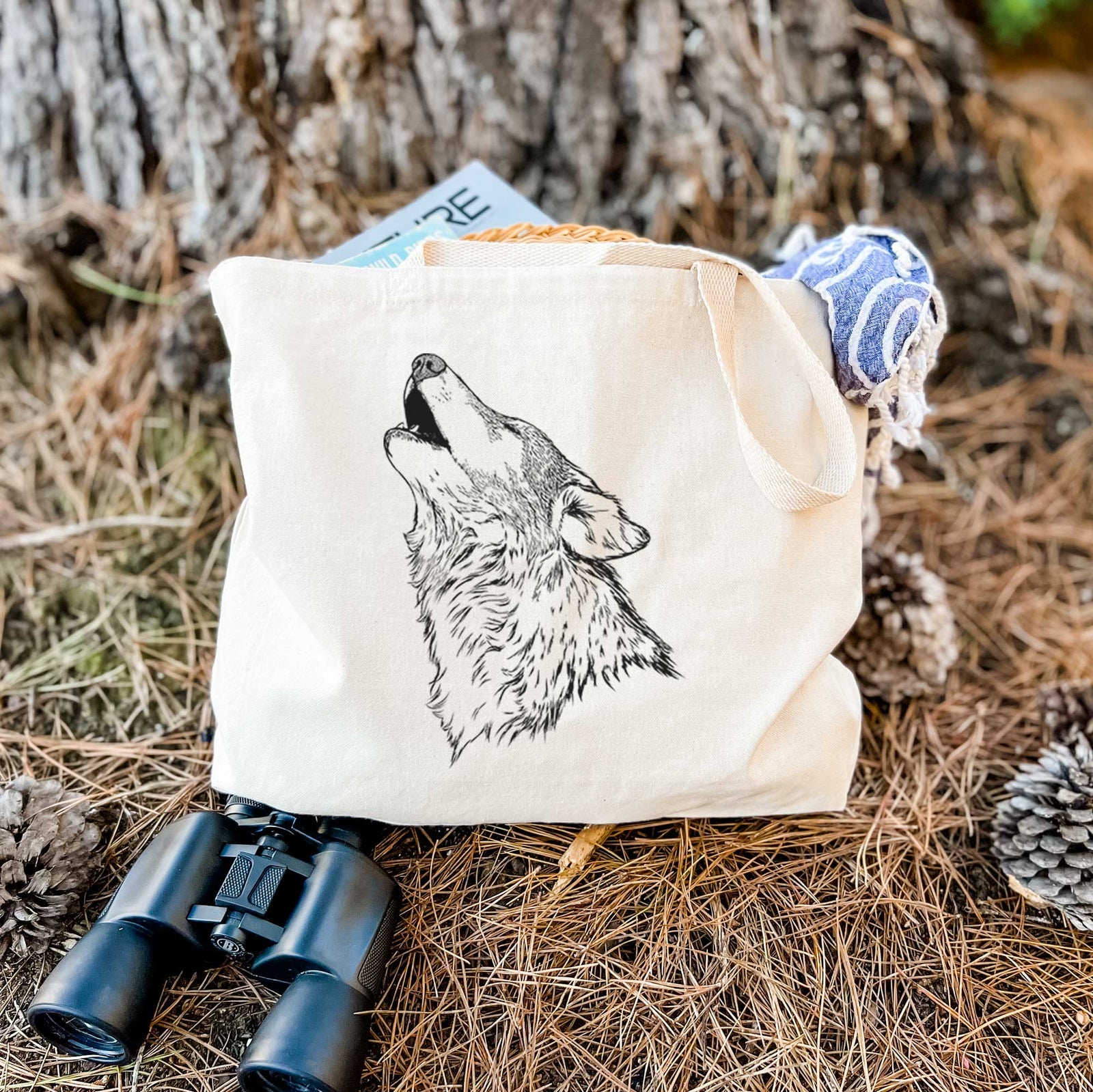 Natural canvas tote bag printed with a detailed black ink illustration of a grey wolf's head and shoulders, howling upward.