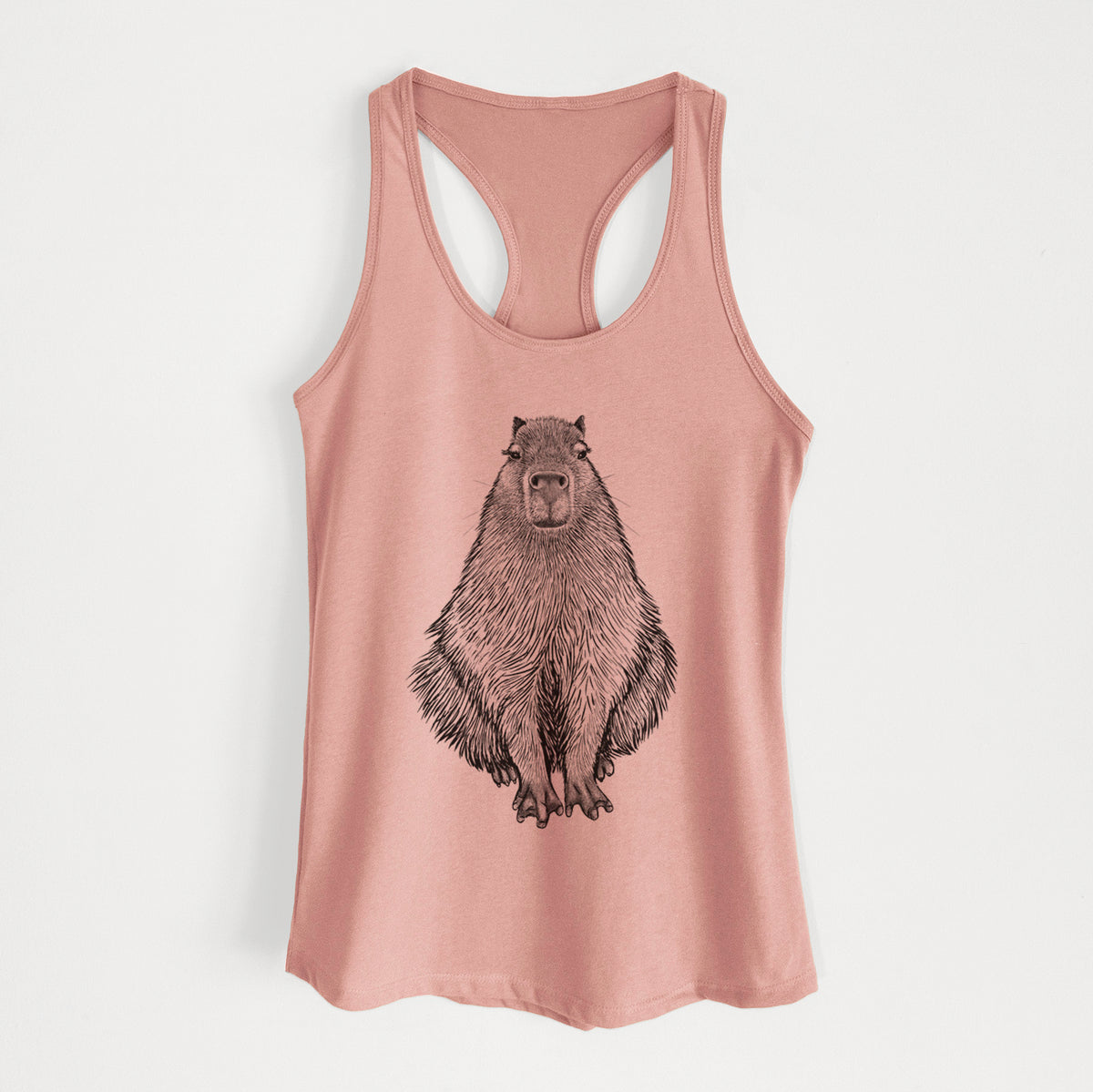 Desert pink women's racerback tank top laid flat, printed with a detailed black ink illustration of a capybara sitting and facing forward.