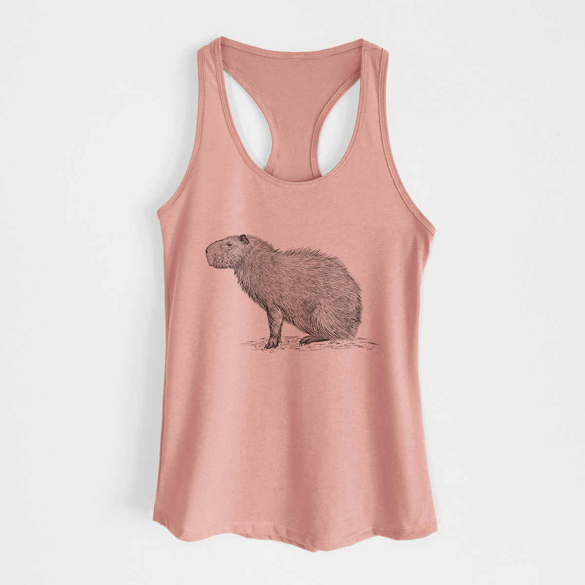 Desert pink women's racerback tank top laid flat, printed with a detailed black ink illustration of a capybara standing in profile.