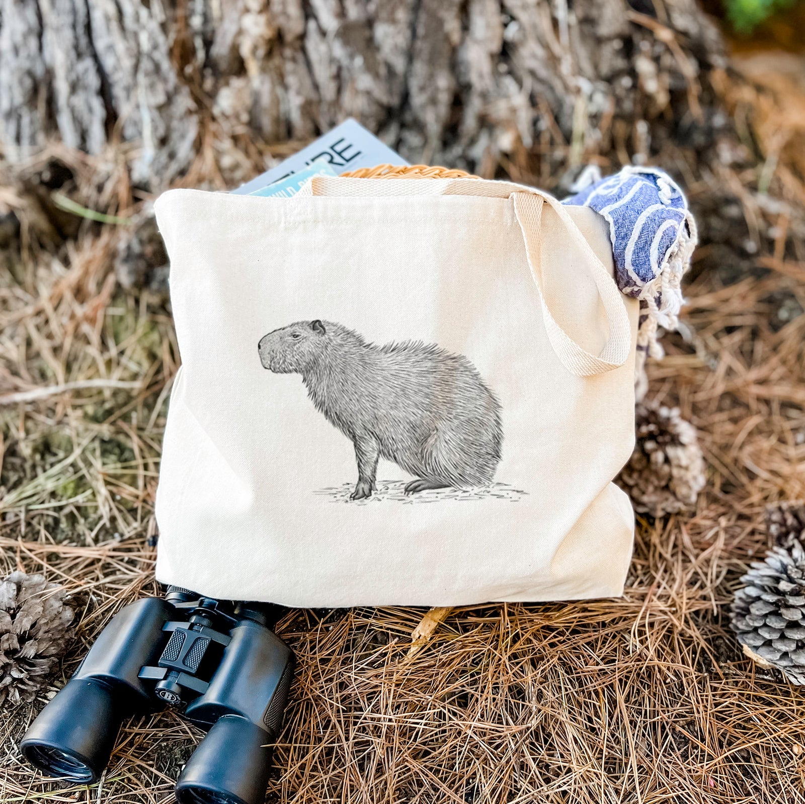 Natural canvas tote bag printed with a detailed black ink illustration of a capybara standing in profile.