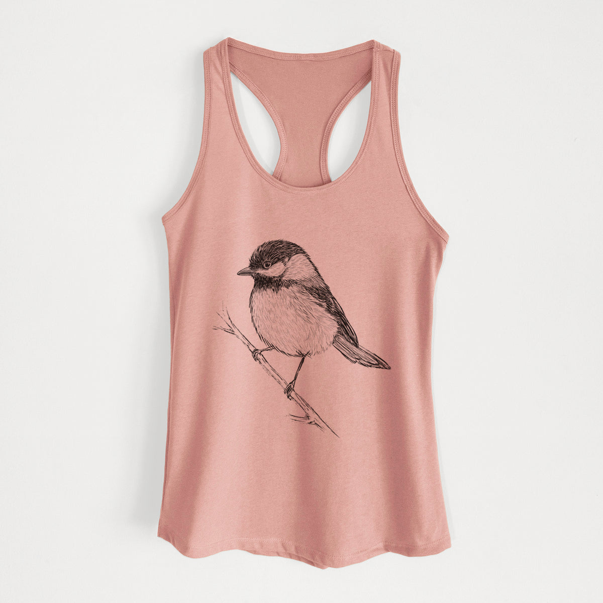 Desert pink women's racerback tank top laid flat, printed with a detailed black ink sketch of a black-capped chickadee perched on a branch.