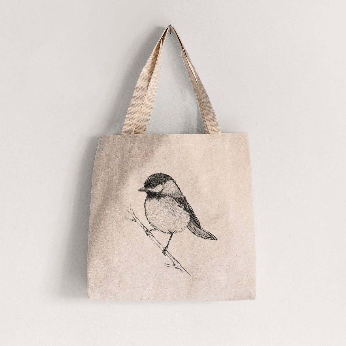 Natural canvas tote bag printed with a detailed black ink sketch of a black-capped chickadee perched on a branch.