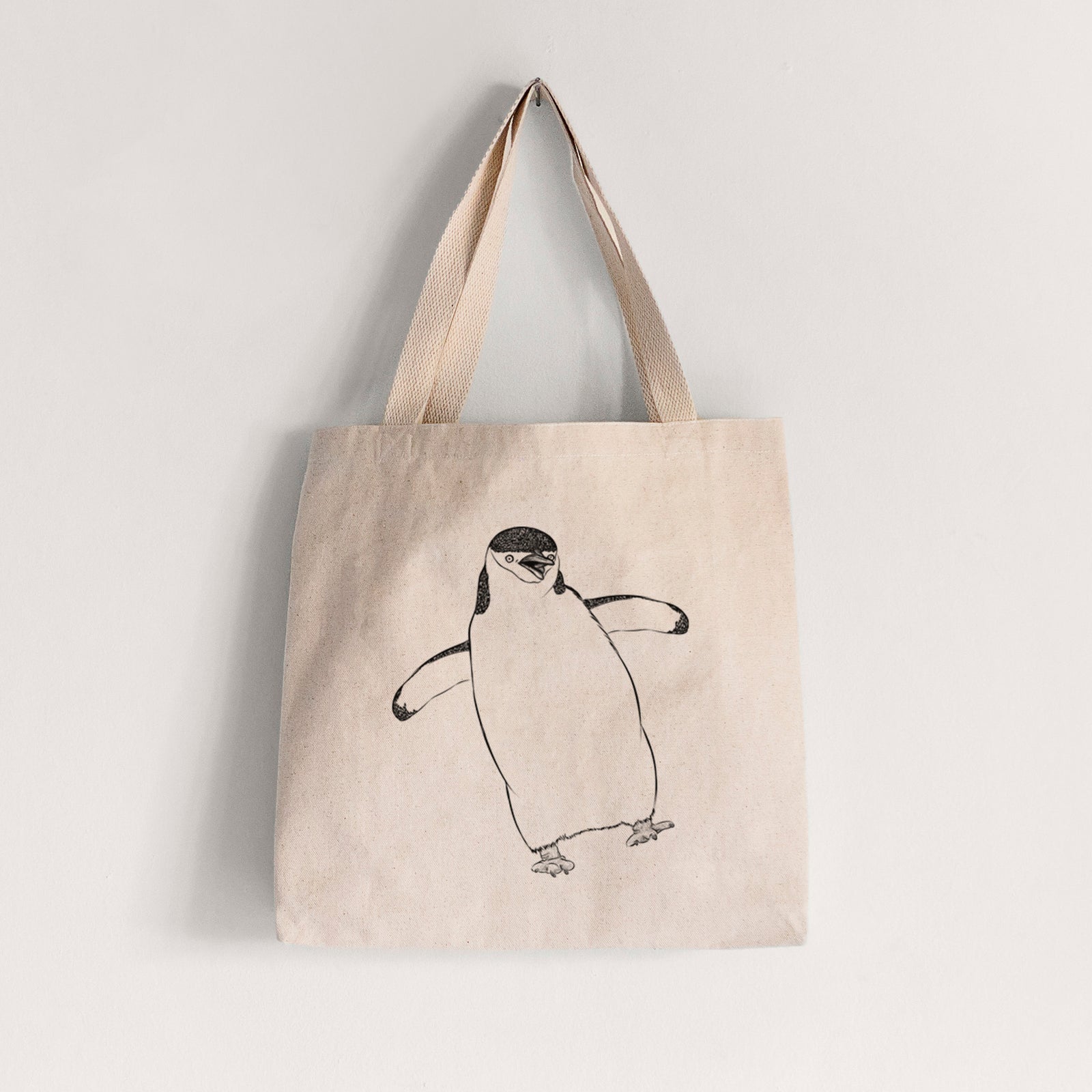 Natural canvas tote bag printed with a black ink illustration of a chinstrap penguin standing with its flippers out.