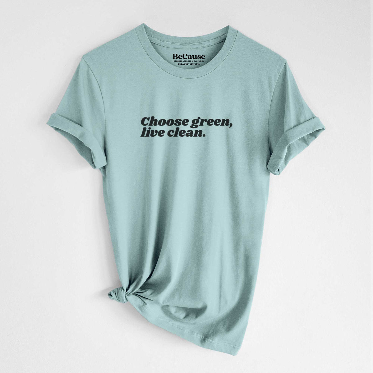 Dusty blue lightweight cotton t-shirt laid flat with the sleeves rolled, printed with small black script words reading Choose Green, Live Clean on the upper chest.