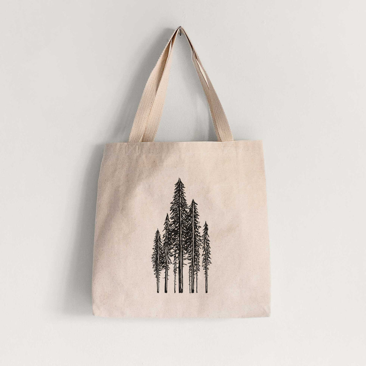 Natural canvas tote bag printed with a black ink illustration of a stand of tall coastal redwood trees with slender trunks and layered branches.