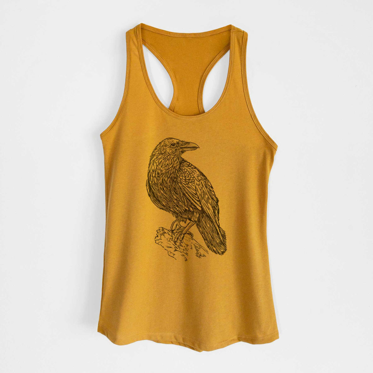 Gold women's racerback tank top laid flat, printed with a detailed black ink sketch of a common raven perched on a rock.