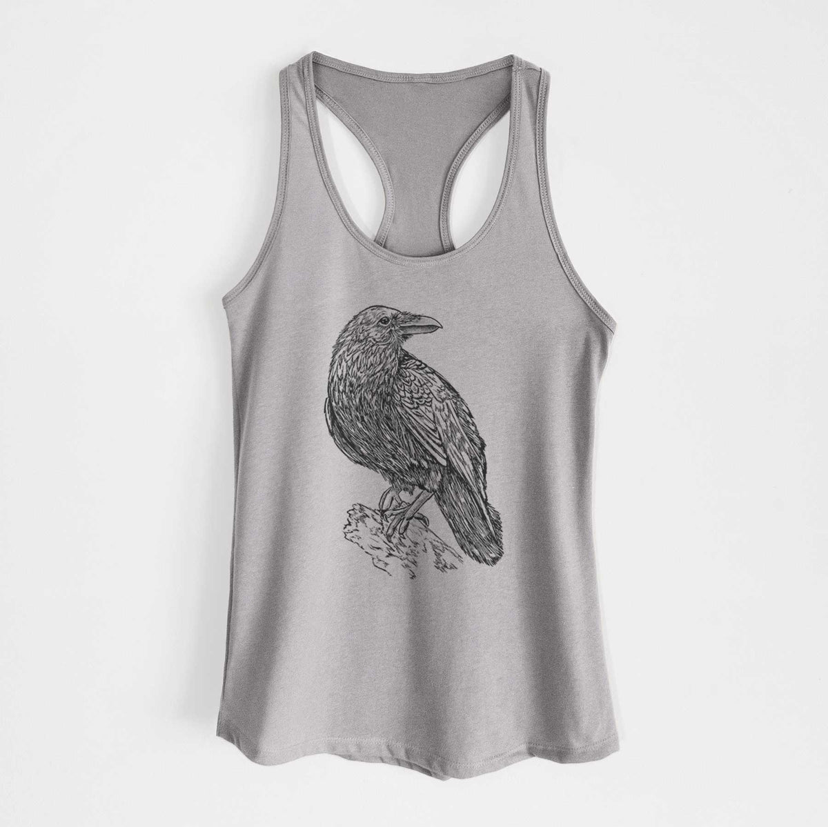 Heather grey women's racerback tank top laid flat, printed with a detailed black ink sketch of a common raven perched on a rock.