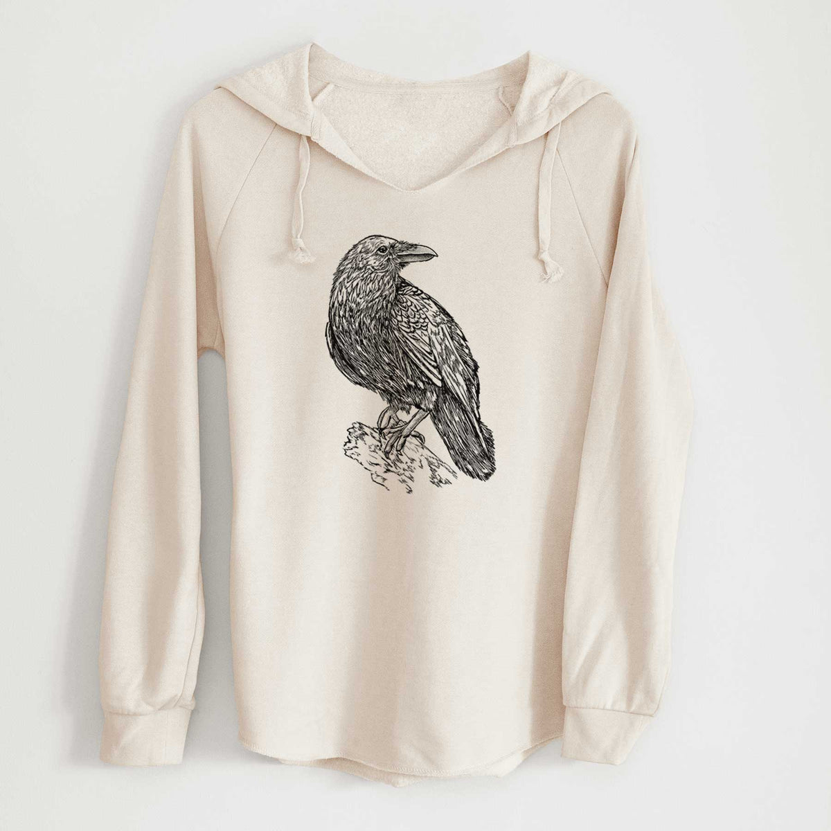 Bone cream women's Cali Wave hooded sweatshirt laid flat, printed with a detailed black ink sketch of a common raven perched on a rock.