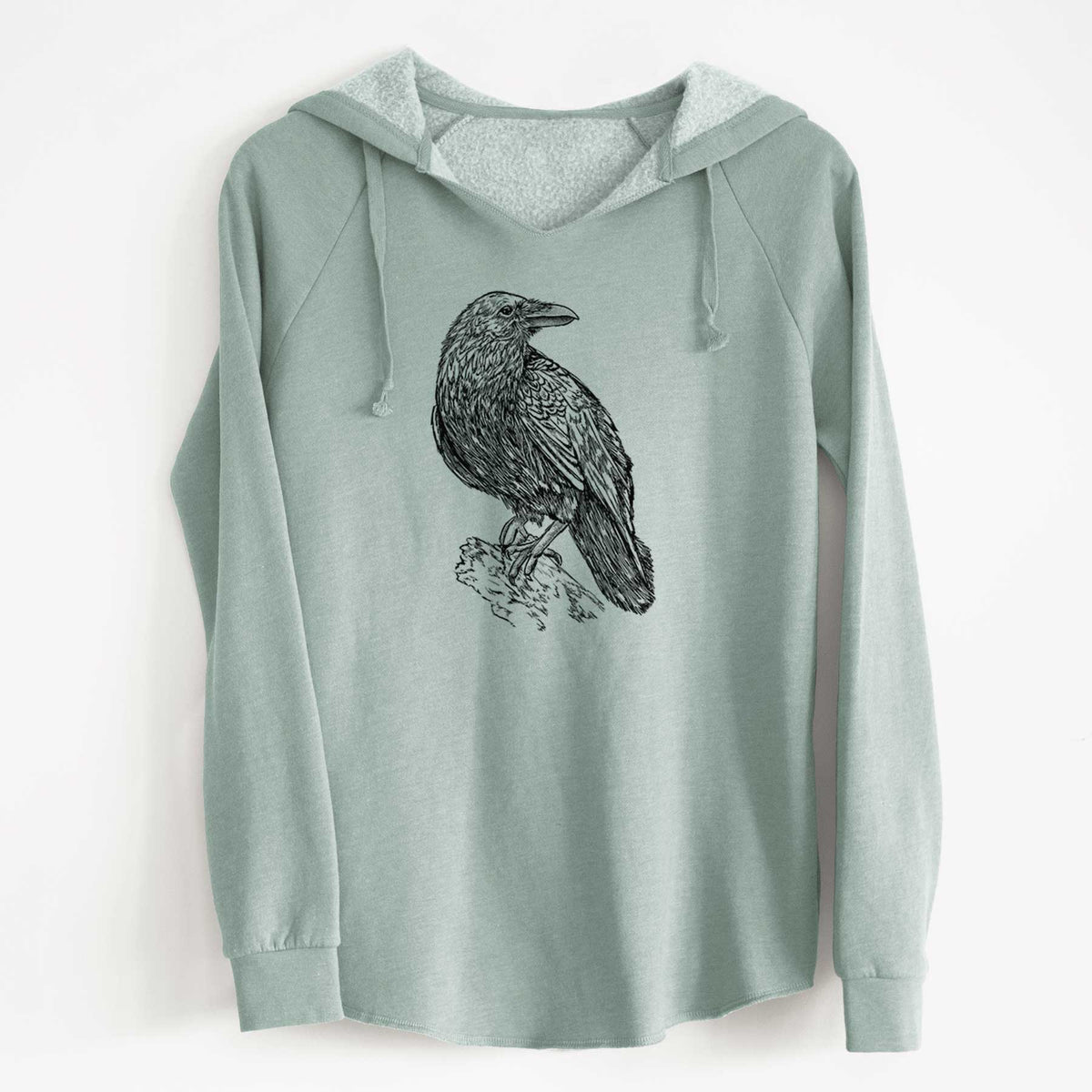 Sage green women's Cali Wave hooded sweatshirt laid flat, printed with a detailed black ink sketch of a common raven perched on a rock.