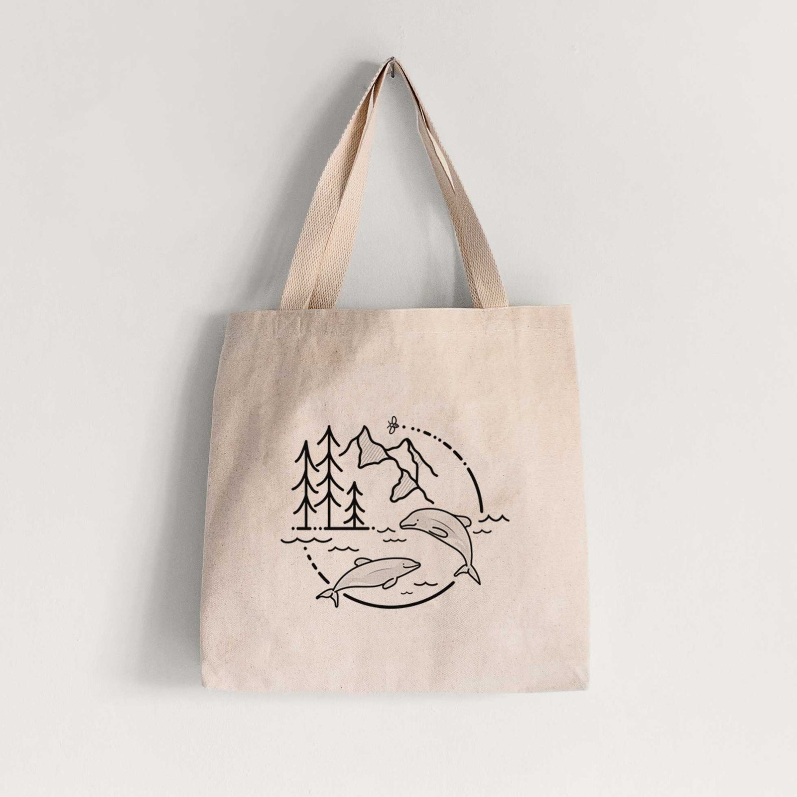 Natural canvas tote bag printed with a black line art circle connecting pine trees, mountains, a bee and two Maui dolphins leaping from the waves.
