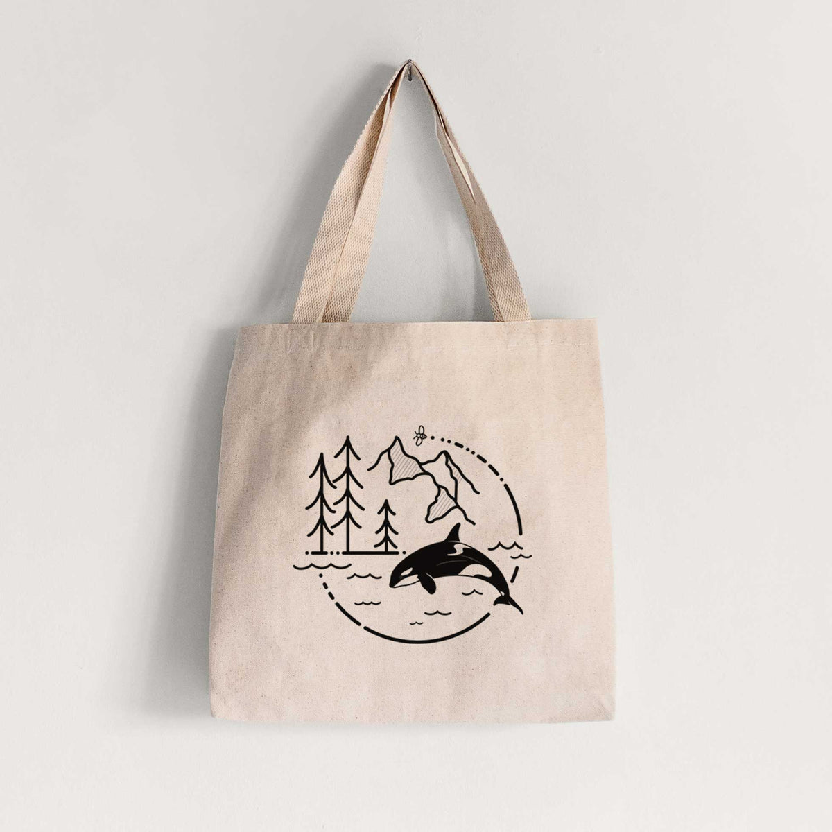 Natural canvas tote bag printed with a black line art circle connecting pine trees, mountains, a bee and an orca leaping from ocean waves.