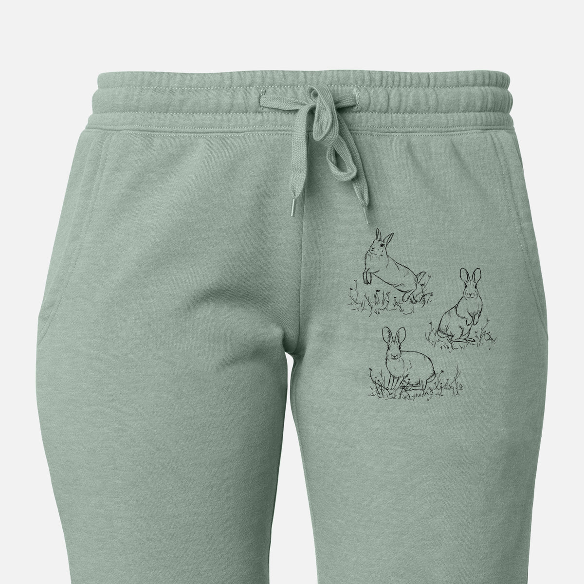 Front of sage green Cali Wave sweatpants, printed with a black ink illustration of three cottontail rabbits among grass and flowers on the leg.