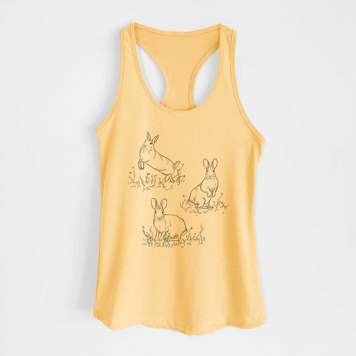 Banana cream women's racerback tank top laid flat, printed with a black ink illustration of three cottontail rabbits among grass and flowers.