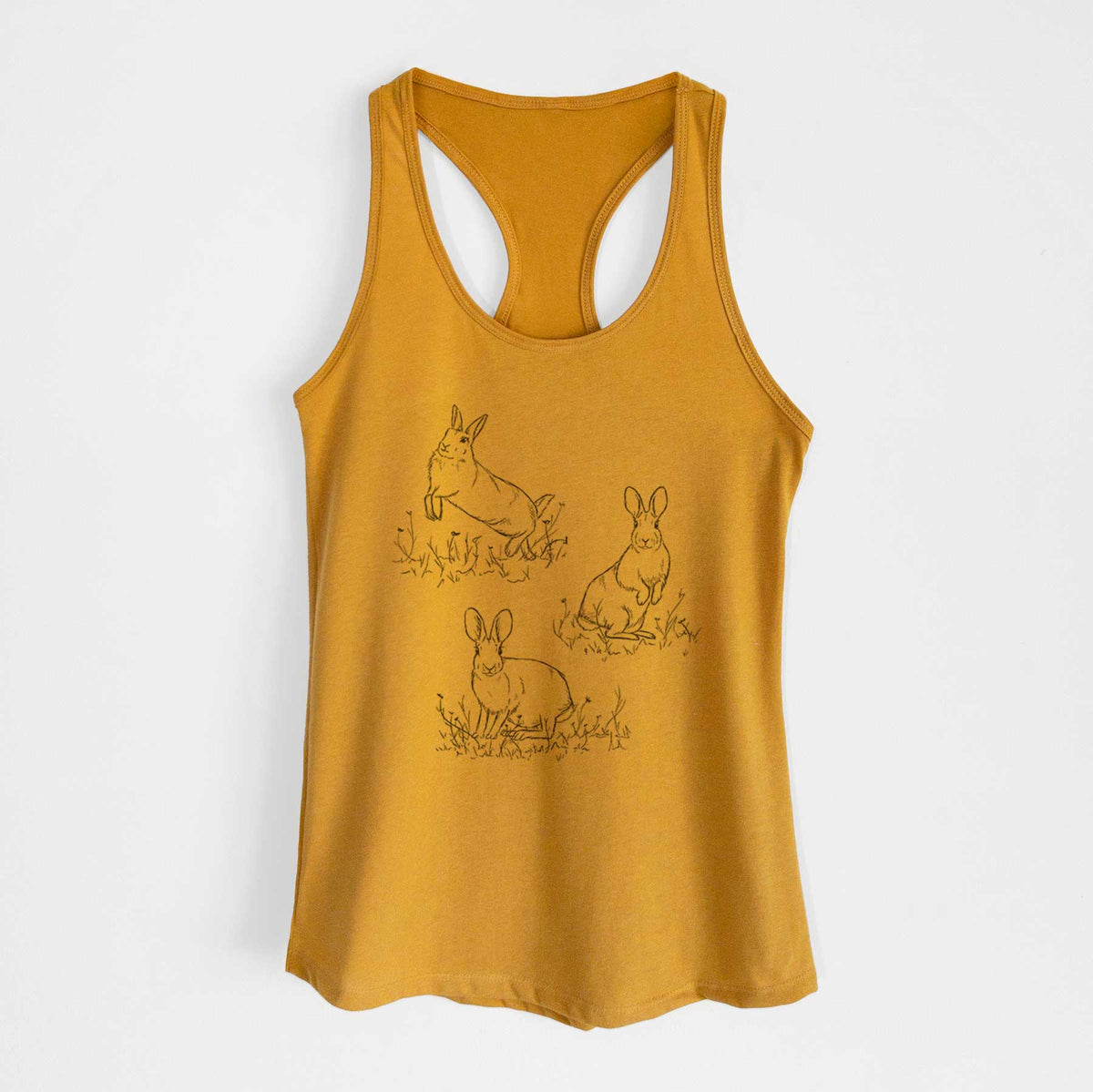 Gold women's racerback tank top laid flat, printed with a black ink illustration of three cottontail rabbits among grass and flowers.
