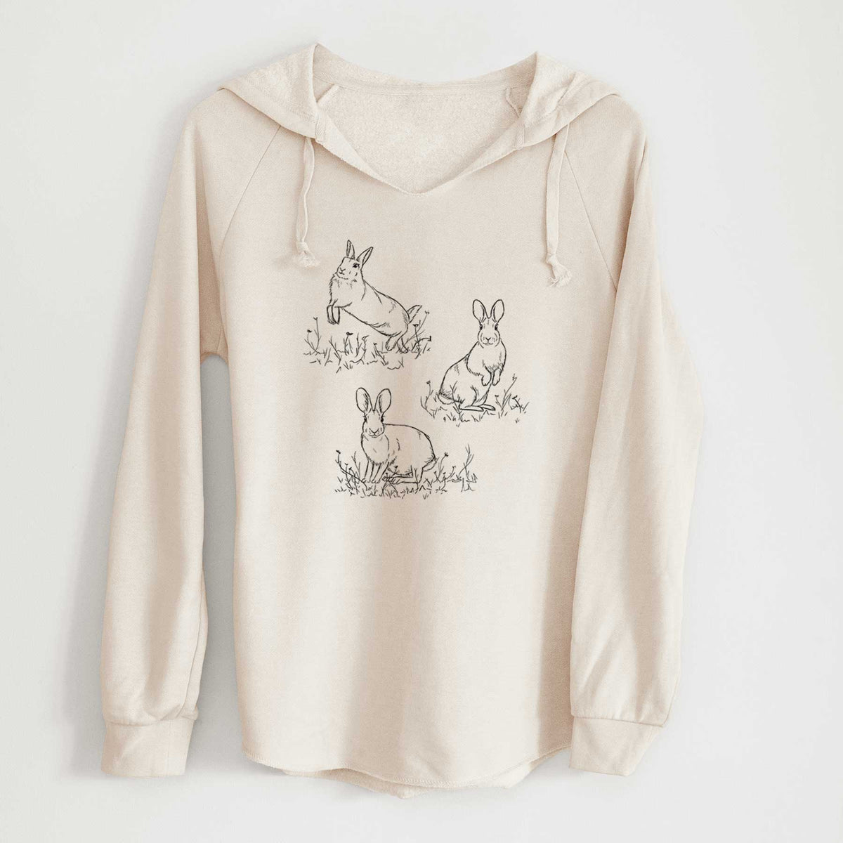 Bone cream women's Cali Wave hooded sweatshirt laid flat, printed with a black ink illustration of three cottontail rabbits among grass and flowers.