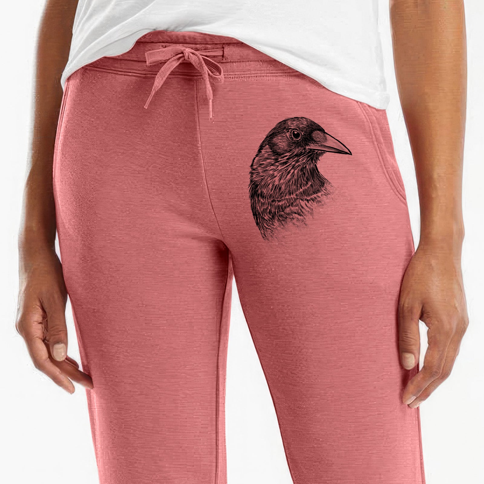 Front of dusty rose Cali Wave sweatpants, printed with a detailed black ink portrait of a crow's head in profile on the leg.