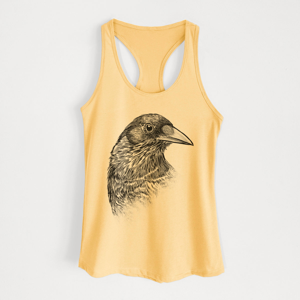 Banana cream women's racerback tank top laid flat, printed with a detailed black ink portrait of a crow's head in profile.