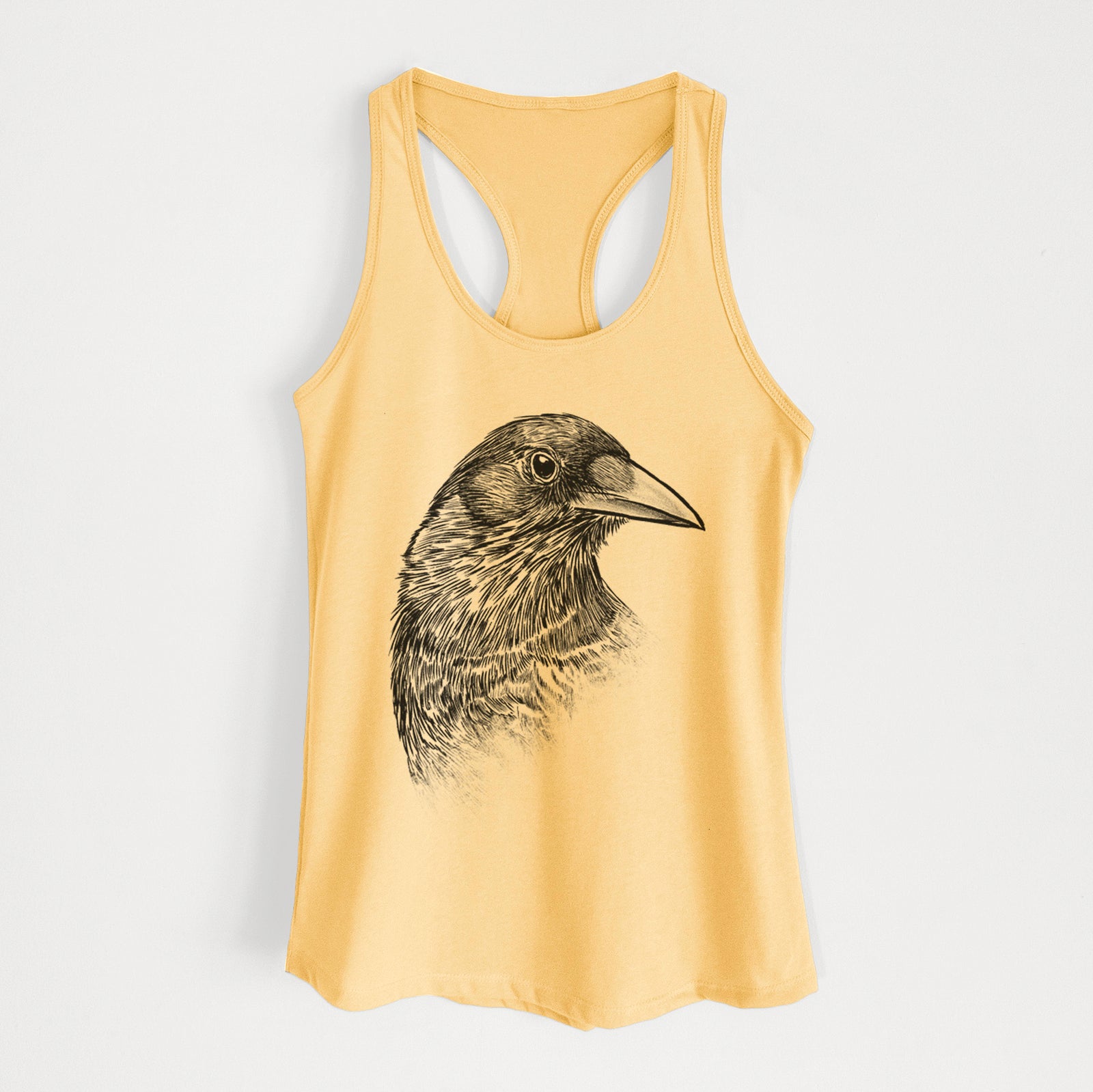 Banana cream women's racerback tank top laid flat, printed with a detailed black ink portrait of a crow's head in profile.