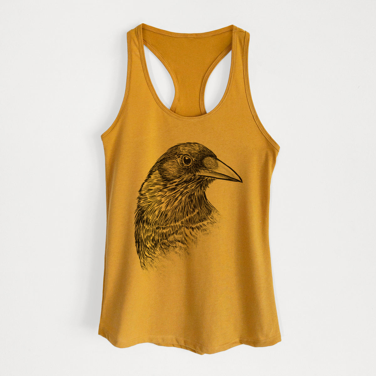 Gold women's racerback tank top laid flat, printed with a detailed black ink portrait of a crow's head in profile.