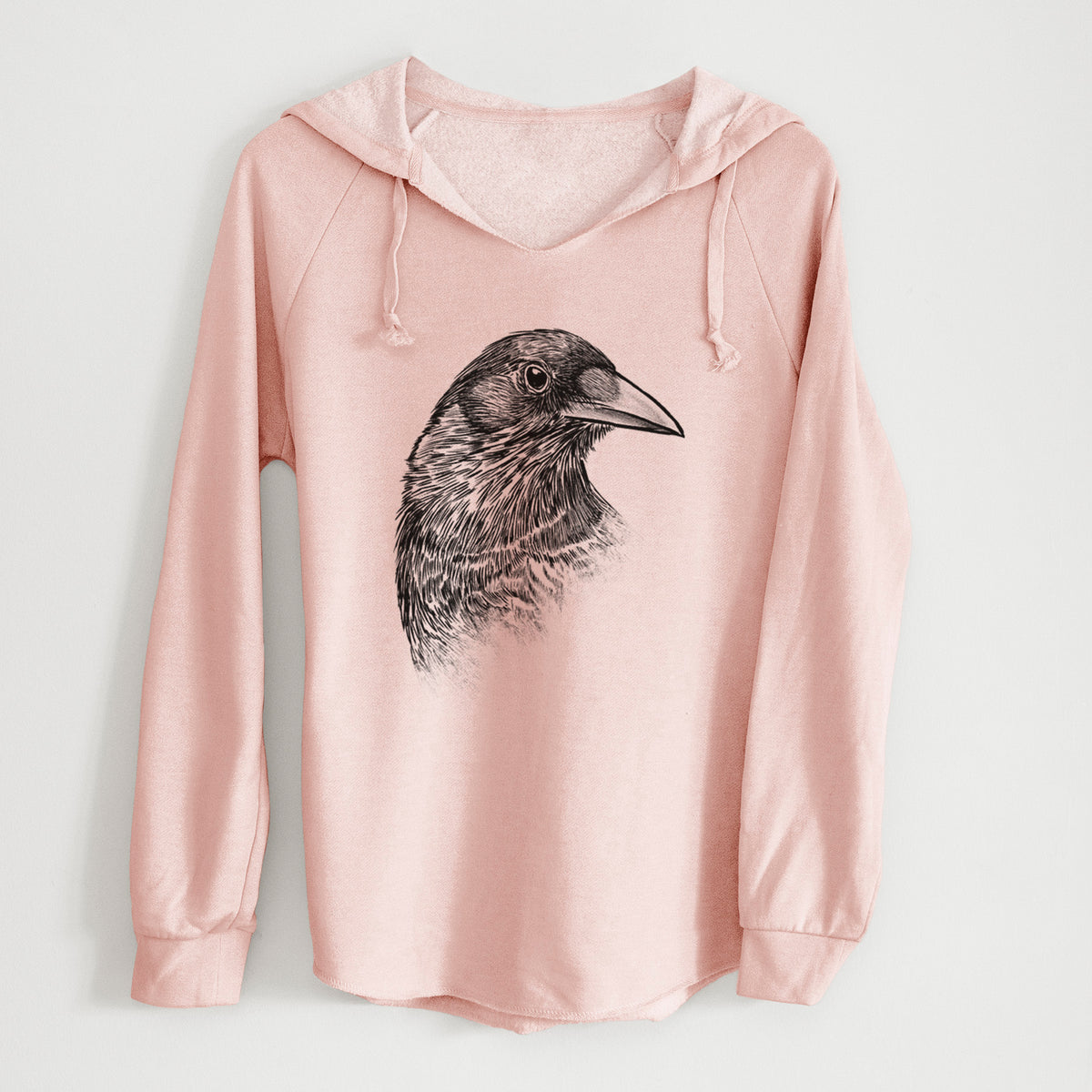 Blush pink women's Cali Wave hooded sweatshirt laid flat, printed with a detailed black ink portrait of a crow's head in profile.