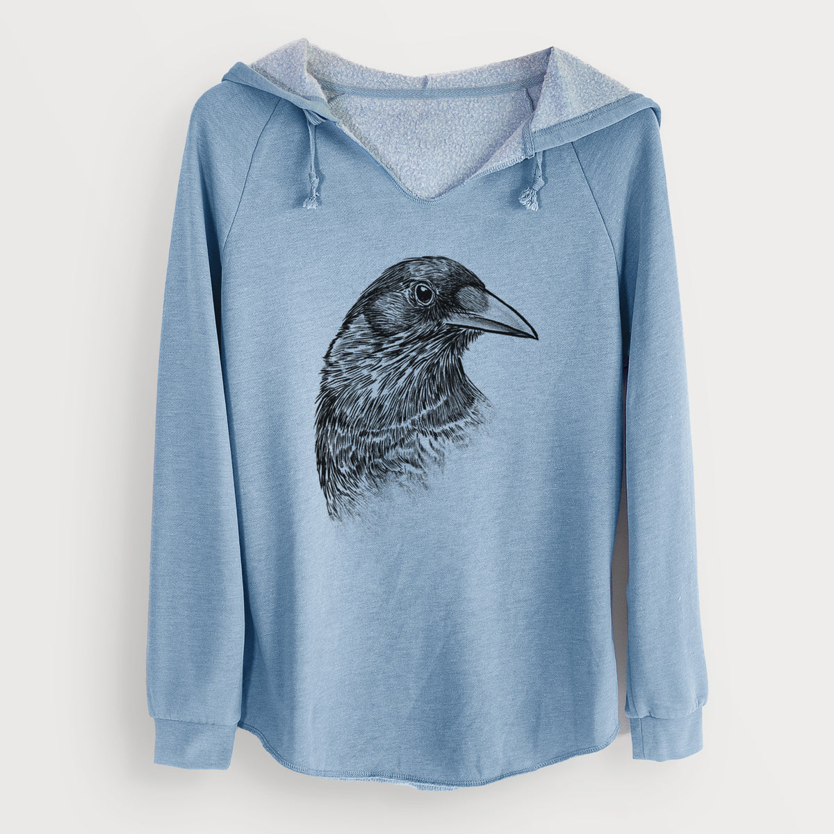 Misty blue women's Cali Wave hooded sweatshirt laid flat, printed with a detailed black ink portrait of a crow's head in profile.