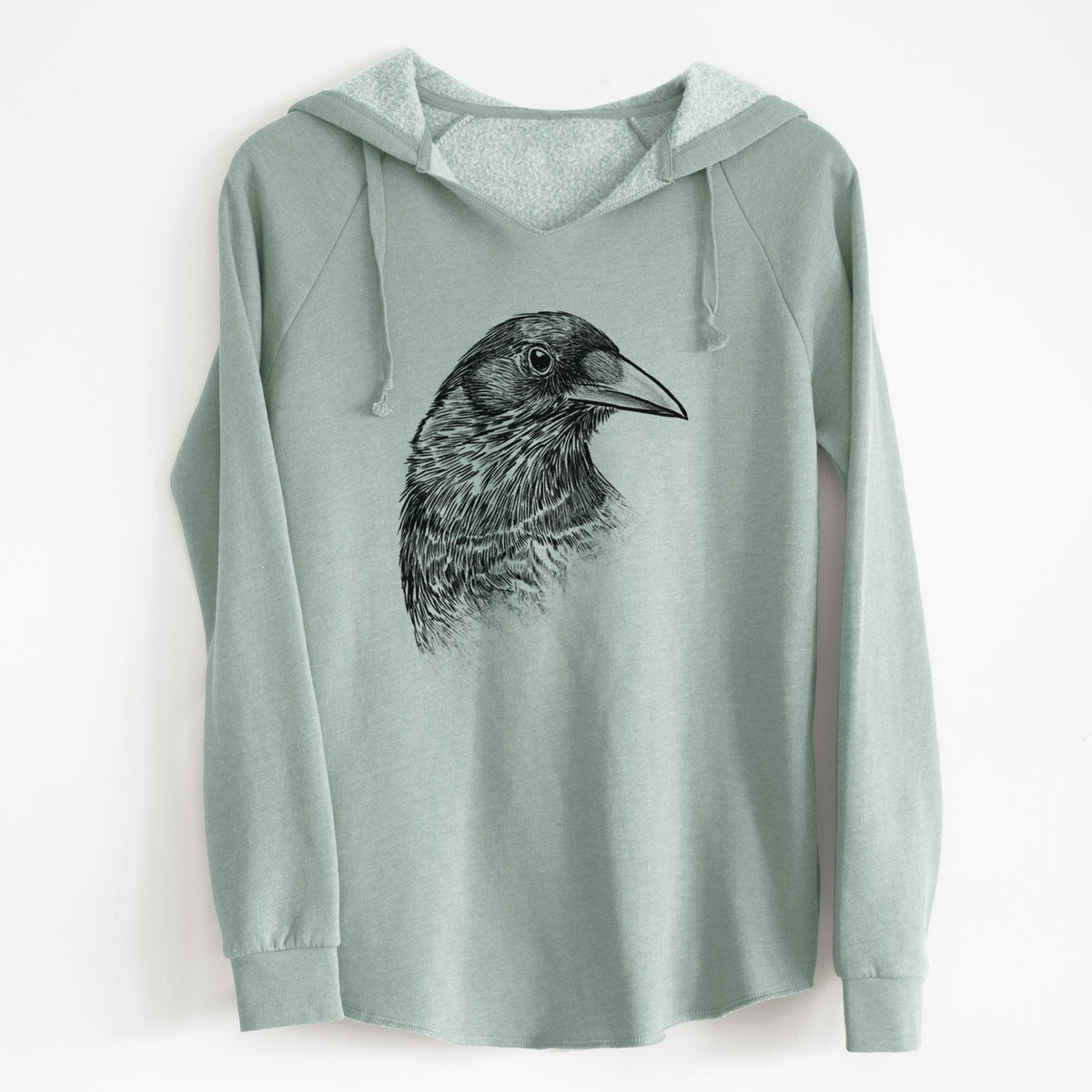 Sage green women's Cali Wave hooded sweatshirt laid flat, printed with a detailed black ink portrait of a crow's head in profile.