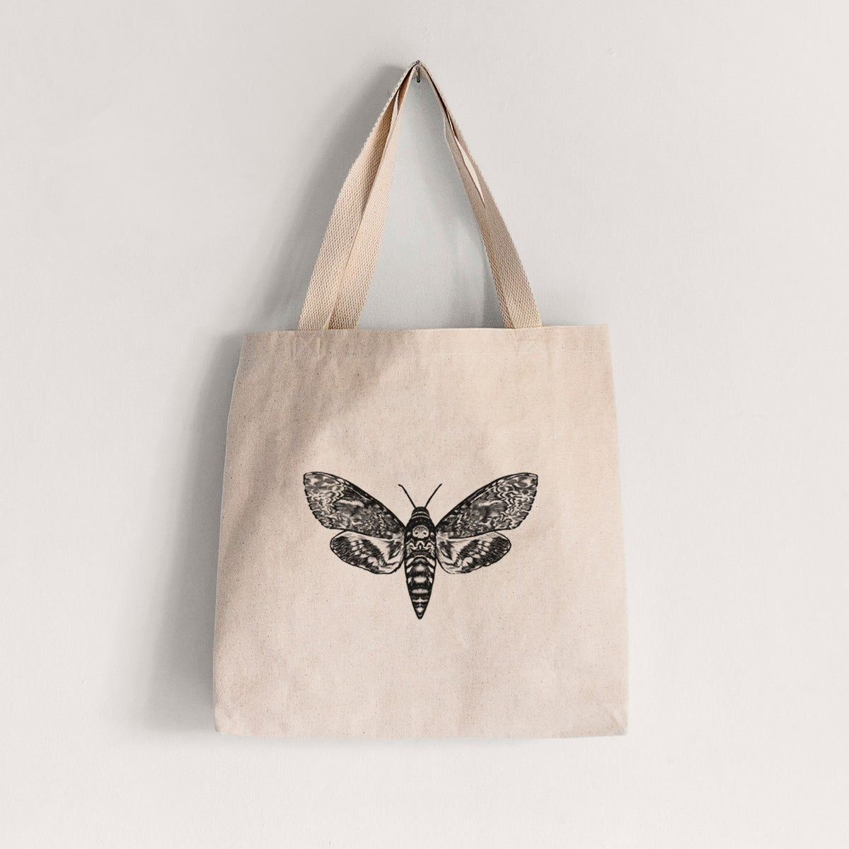 Natural canvas tote bag printed with a detailed black ink illustration of a death's-head hawkmoth with its wings spread.