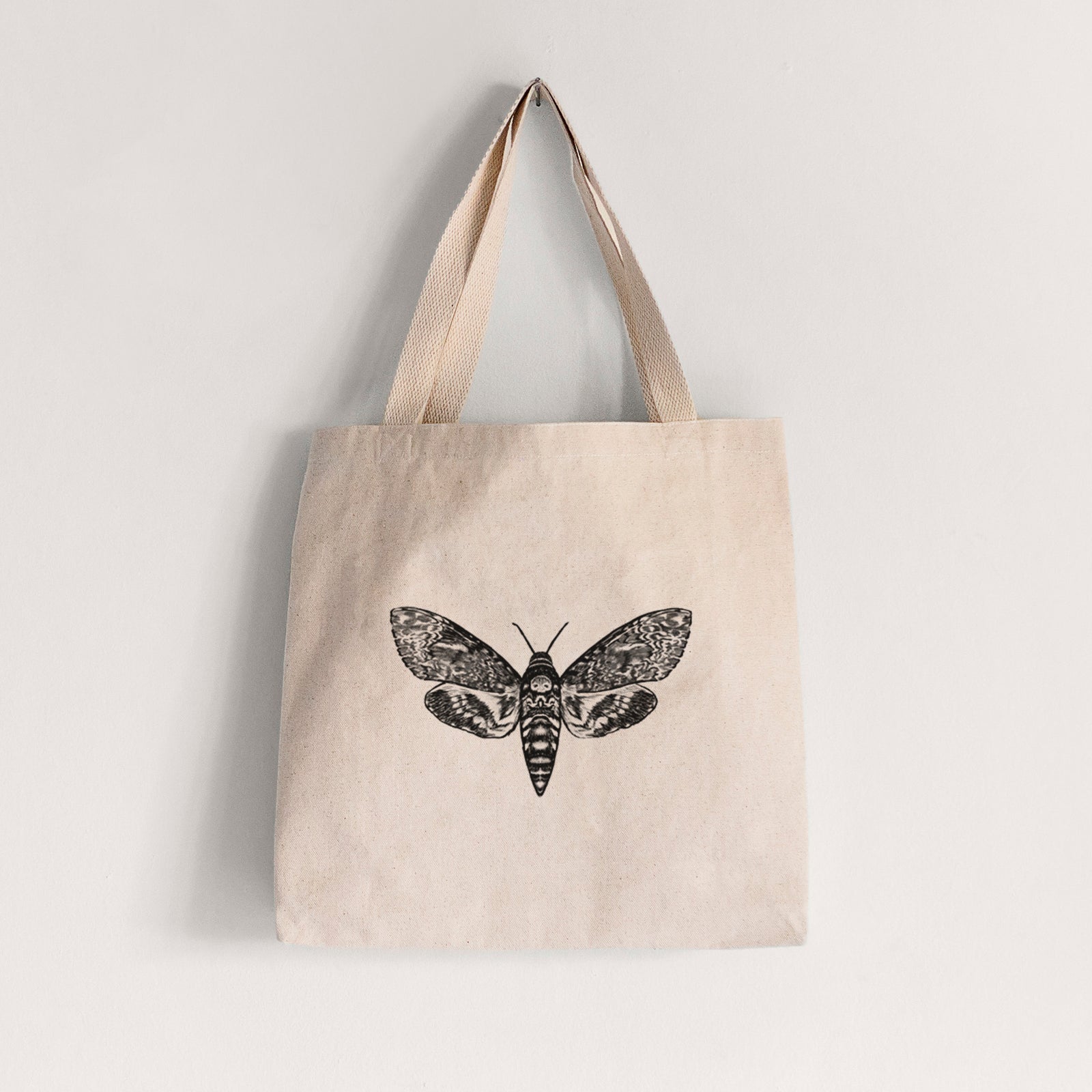 Natural canvas tote bag printed with a detailed black ink illustration of a death's-head hawkmoth with its wings spread.