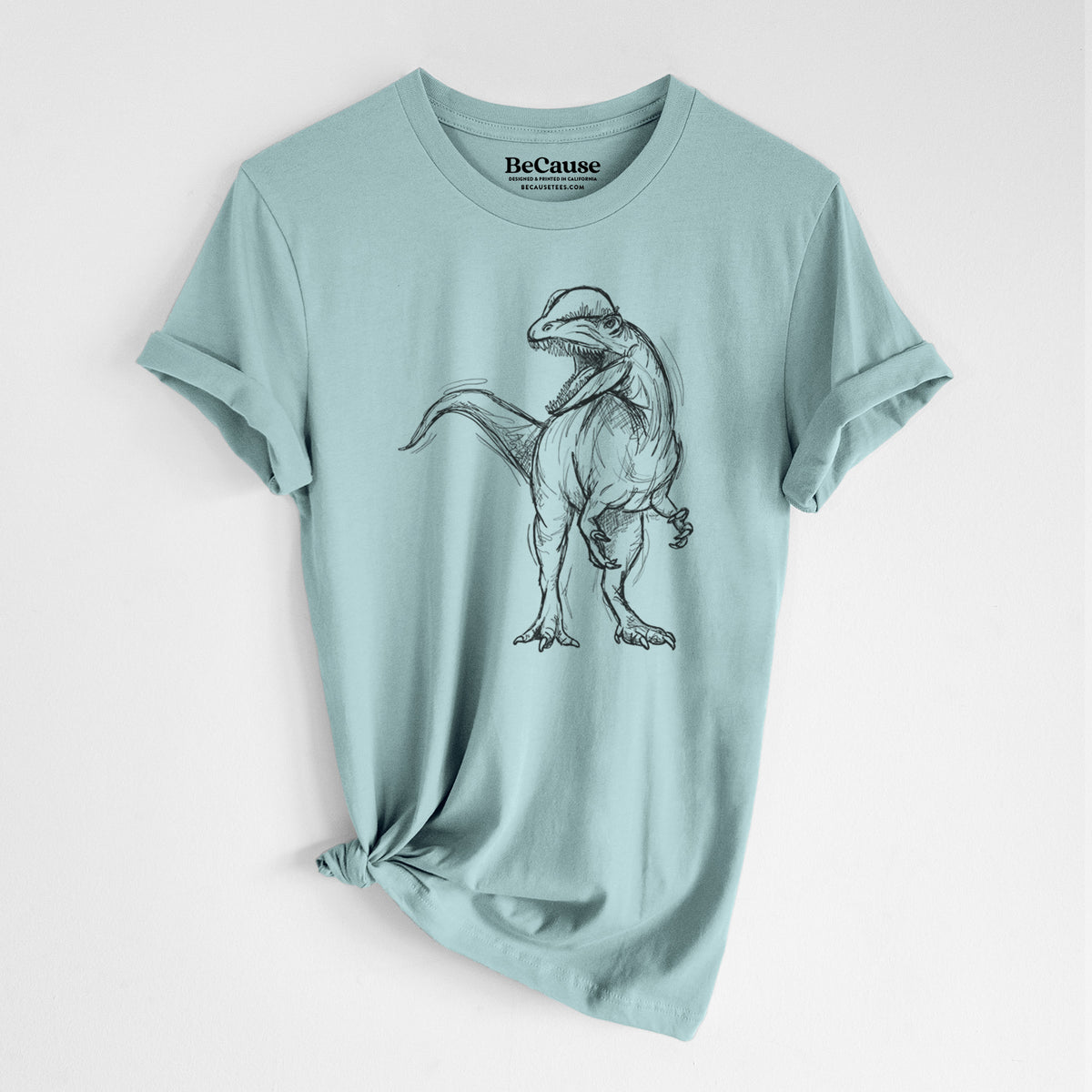 Dusty blue lightweight cotton t-shirt laid flat with the sleeves rolled, printed with a black ink illustration of a Dilophosaurus with its neck frill, walking.