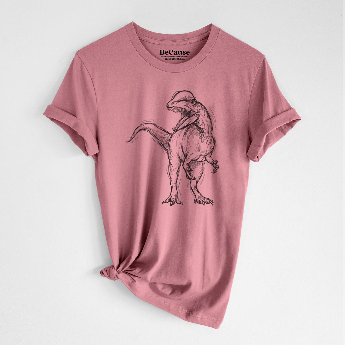 Mauve pink lightweight cotton t-shirt laid flat with the sleeves rolled, printed with a black ink illustration of a Dilophosaurus with its neck frill, walking.