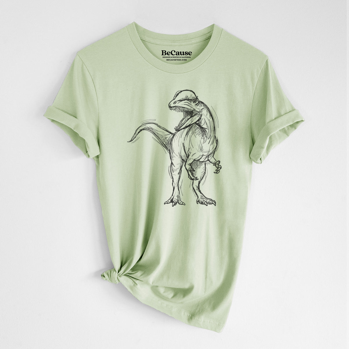 Spring green lightweight cotton t-shirt laid flat with the sleeves rolled, printed with a black ink illustration of a Dilophosaurus with its neck frill, walking.