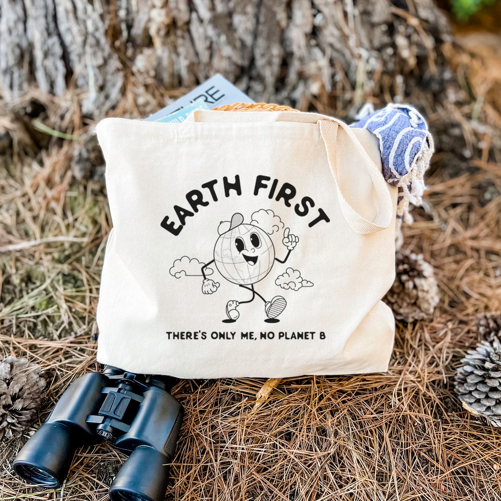 Natural canvas tote bag printed with a cheerful cartoon Earth running, with the words Earth First and There's Only Me, No Planet B.
