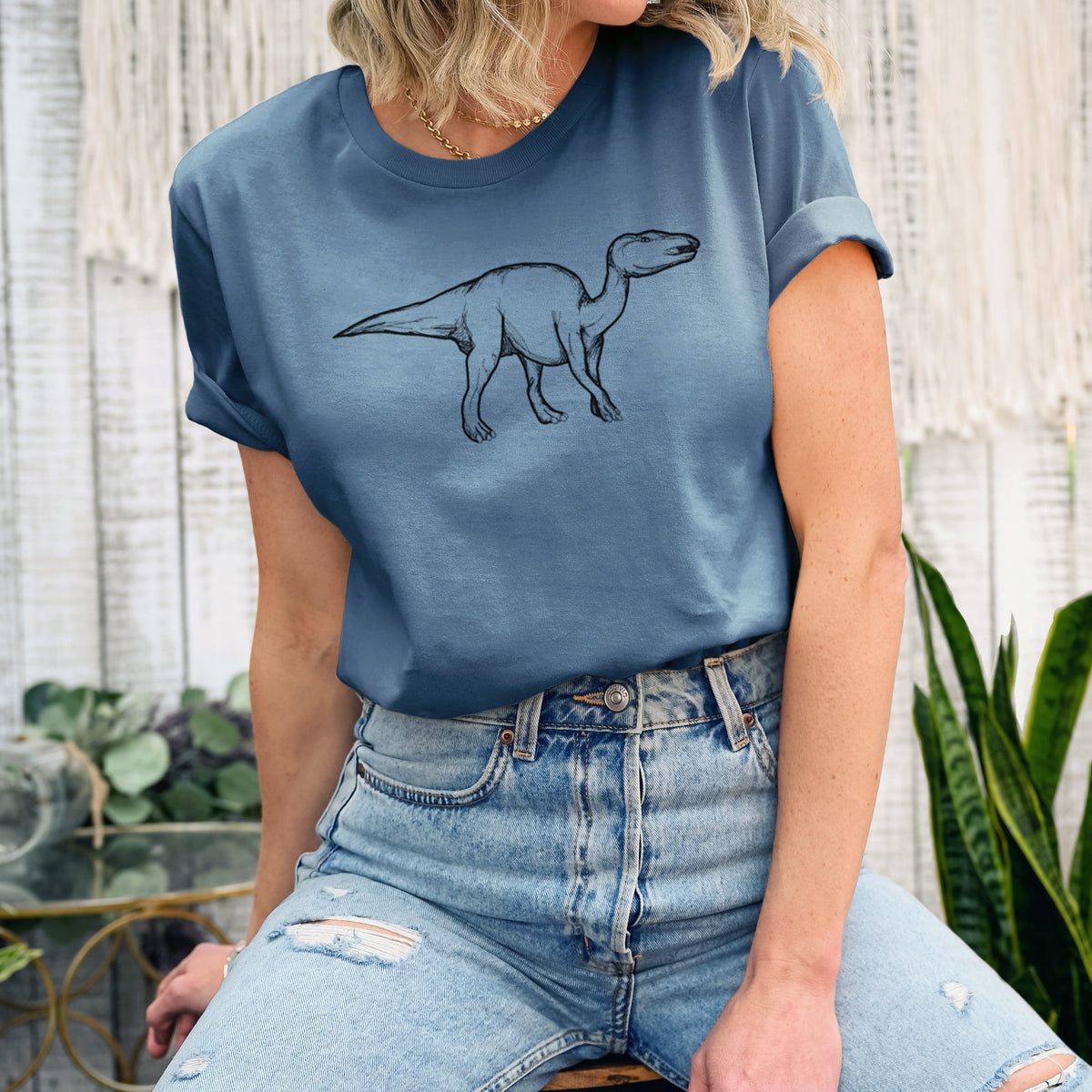 Woman wearing a steel blue lightweight cotton t-shirt printed with a black ink illustration of an Edmontosaurus walking.