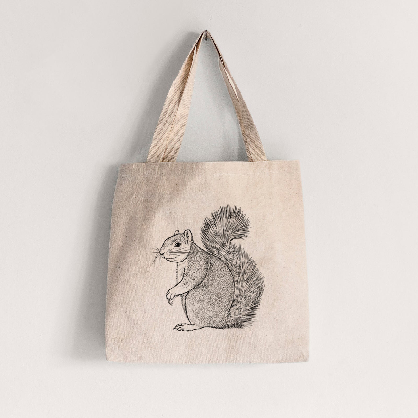 Natural canvas tote bag printed with a detailed black ink illustration of a fox squirrel sitting with a bushy tail.