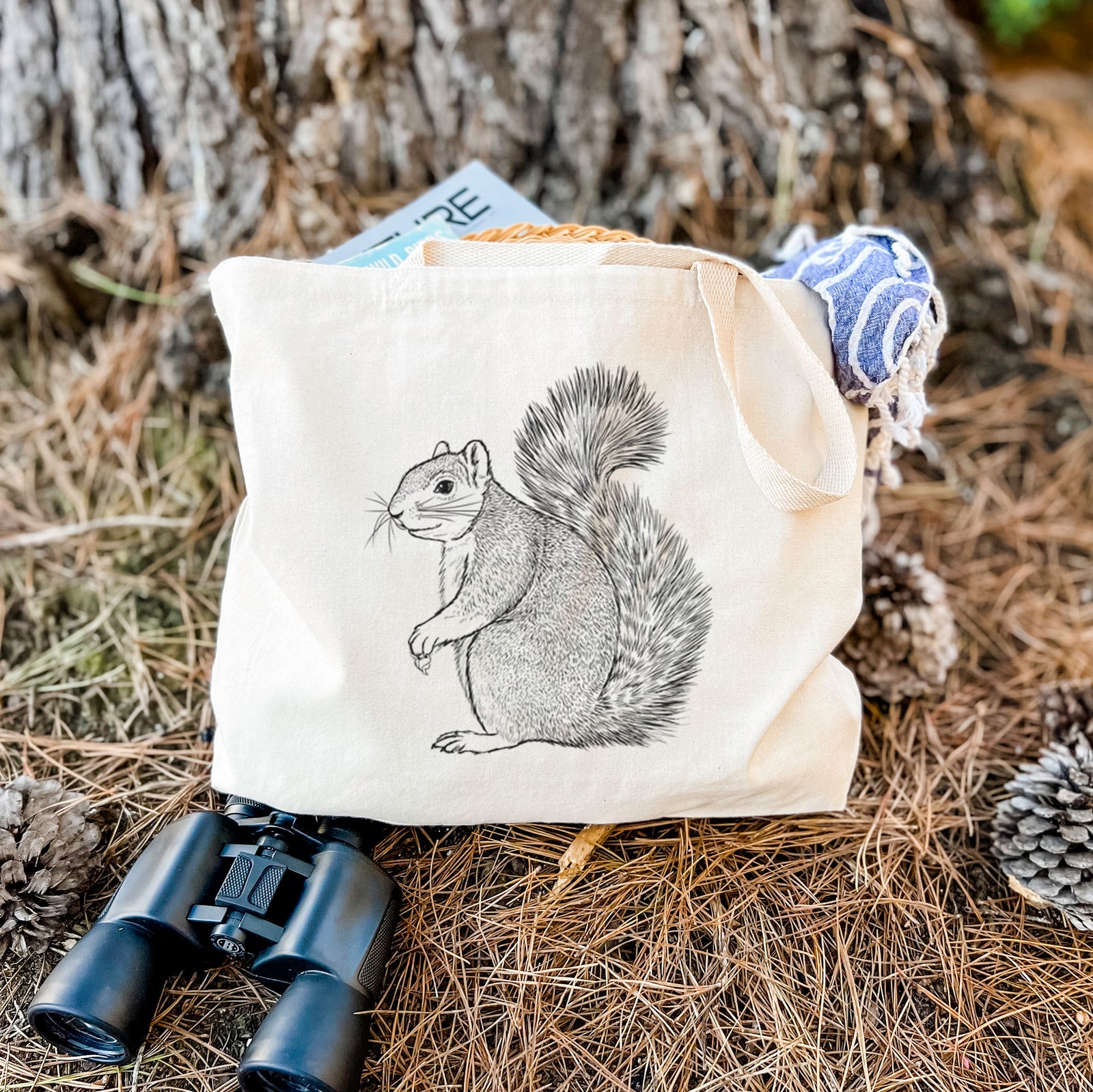 Natural canvas tote bag printed with a detailed black ink illustration of a fox squirrel sitting with a bushy tail.