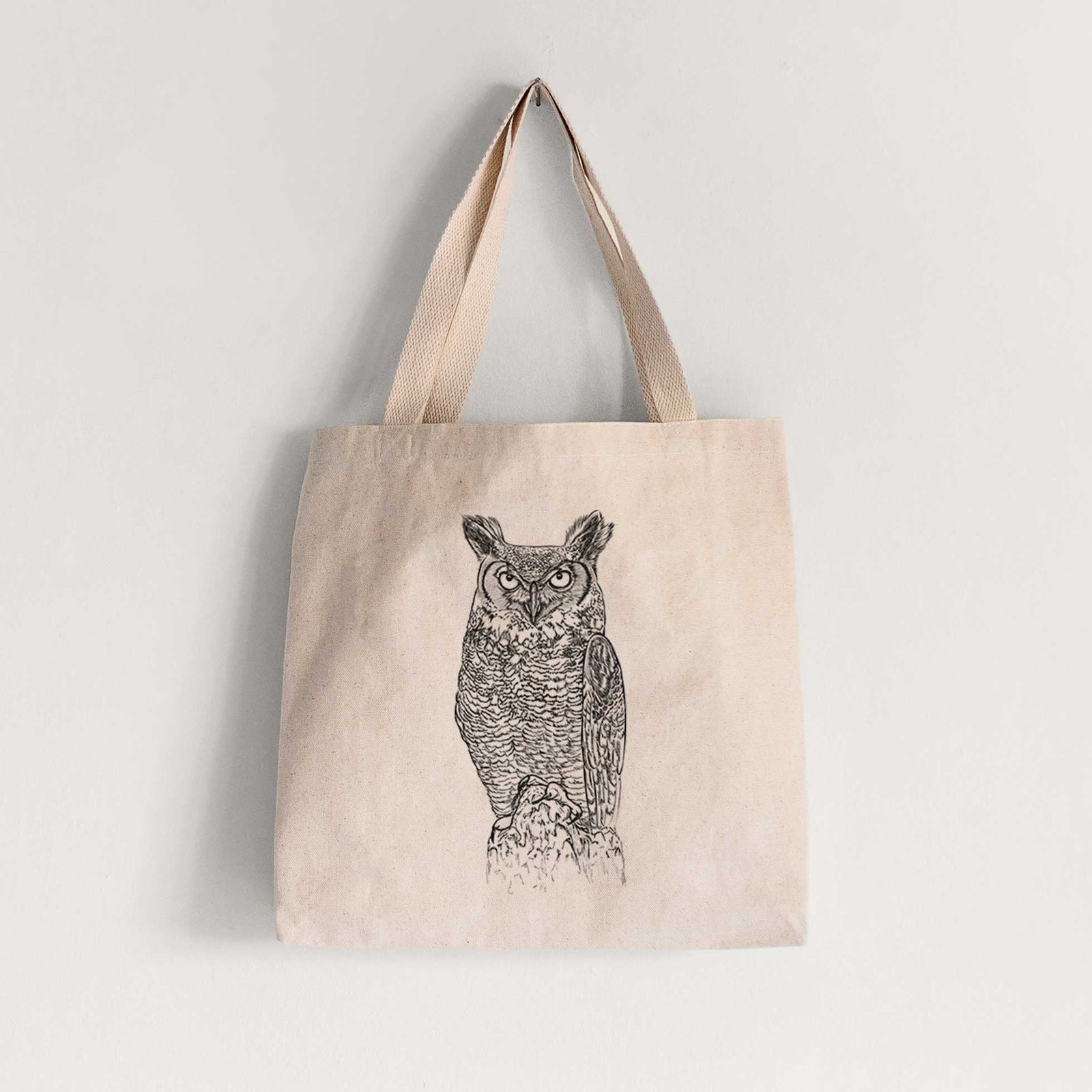 Natural canvas tote bag printed with a detailed black ink illustration of a great horned owl standing upright with its ear tufts raised.