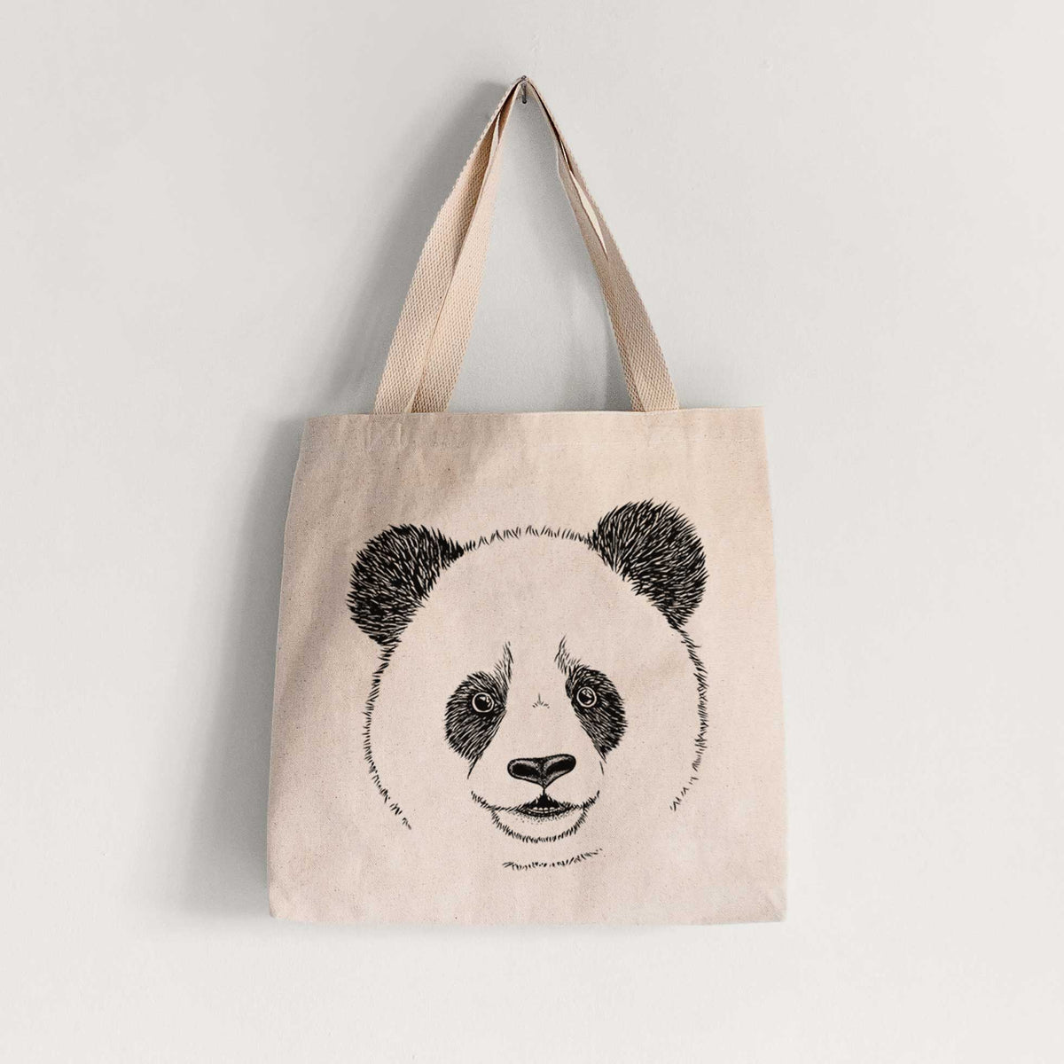 Natural canvas tote bag printed with a black ink portrait of a smiling giant panda's face.