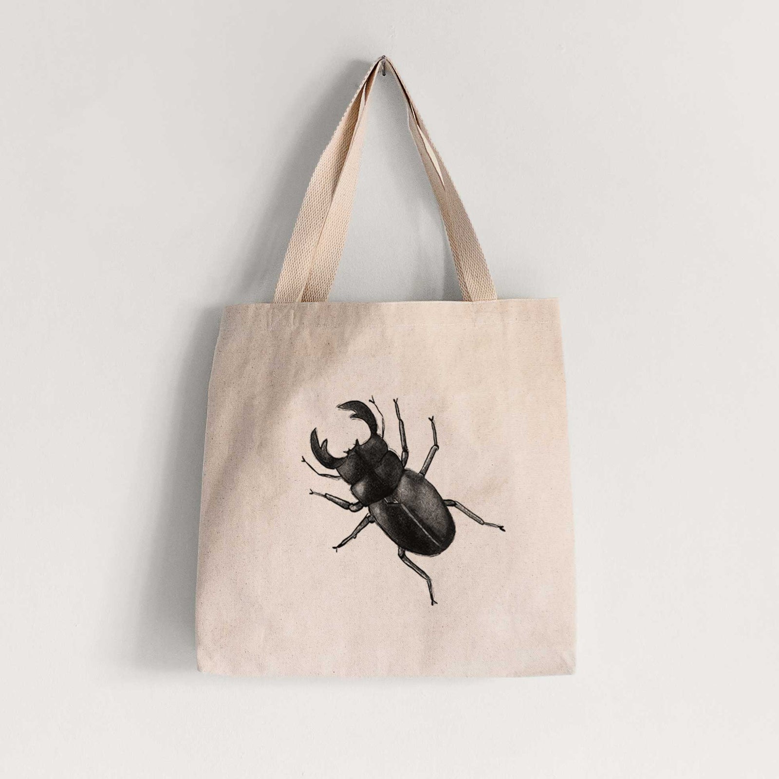 Natural canvas tote bag printed with a detailed black ink illustration of a giant stag beetle with large jaws, seen from above.