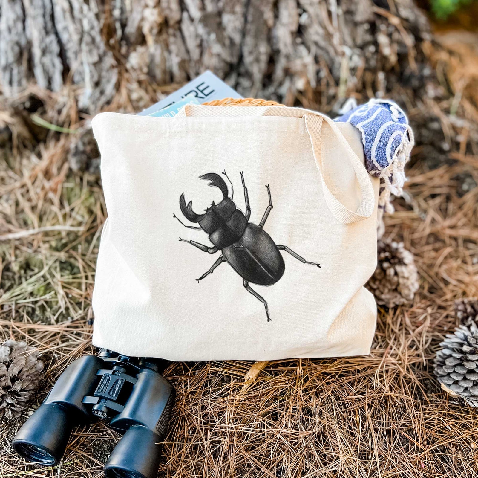 Natural canvas tote bag printed with a detailed black ink illustration of a giant stag beetle with large jaws, seen from above.