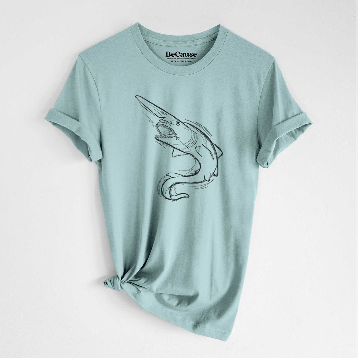 Dusty blue lightweight cotton t-shirt laid flat with the sleeves rolled, printed with a black ink illustration of a goblin shark with its long snout, swimming in a curve.