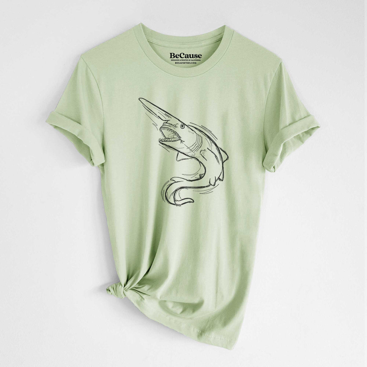 Spring green lightweight cotton t-shirt laid flat with the sleeves rolled, printed with a black ink illustration of a goblin shark with its long snout, swimming in a curve.