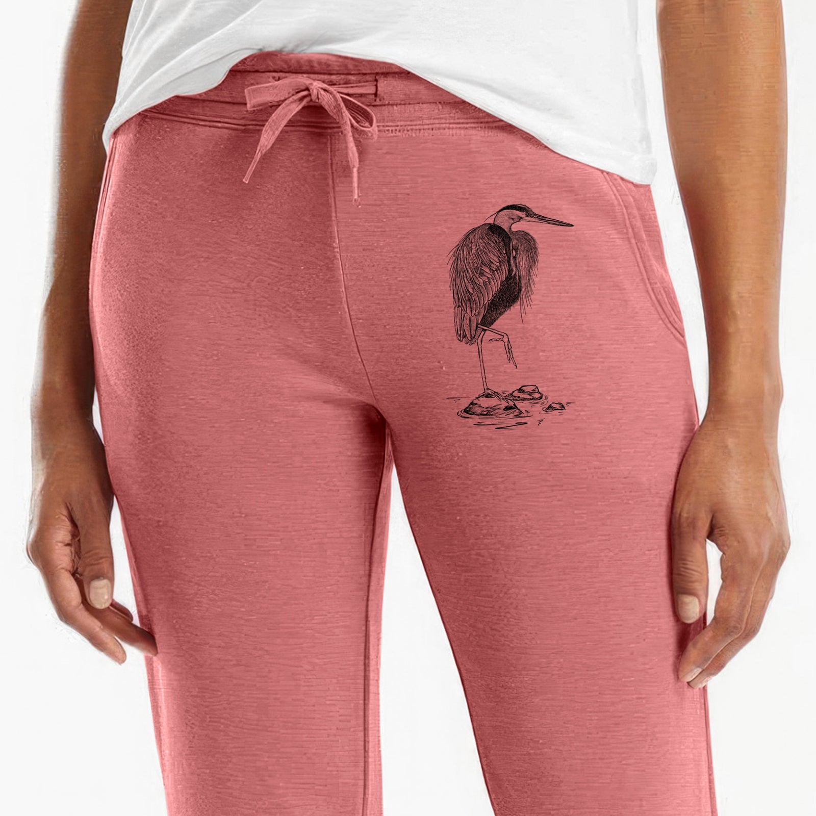 Front of dusty rose Cali Wave sweatpants, printed with a detailed black ink illustration of a great blue heron standing on rocks on the leg.