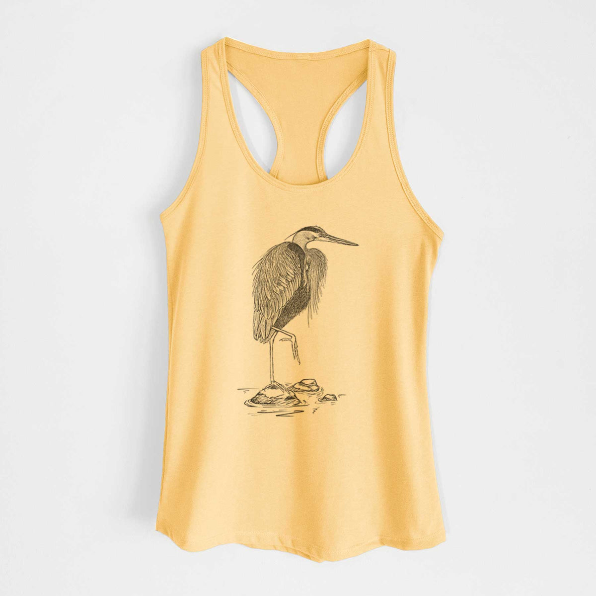 Banana cream women's racerback tank top laid flat, printed with a detailed black ink illustration of a great blue heron standing on rocks.