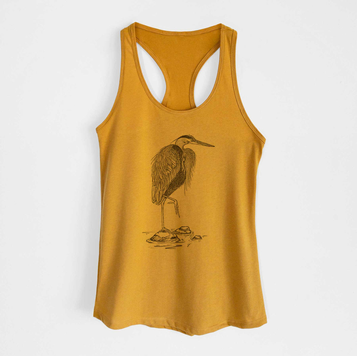 Gold women's racerback tank top laid flat, printed with a detailed black ink illustration of a great blue heron standing on rocks.