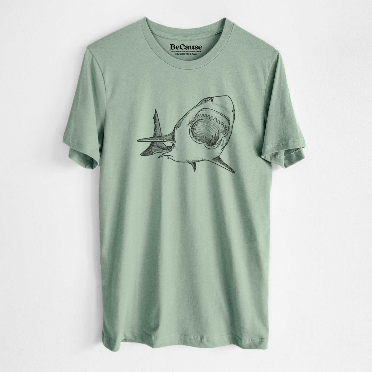 Sage green lightweight cotton t-shirt laid flat, printed with a black ink illustration of a great white shark swimming toward the viewer with its mouth open.