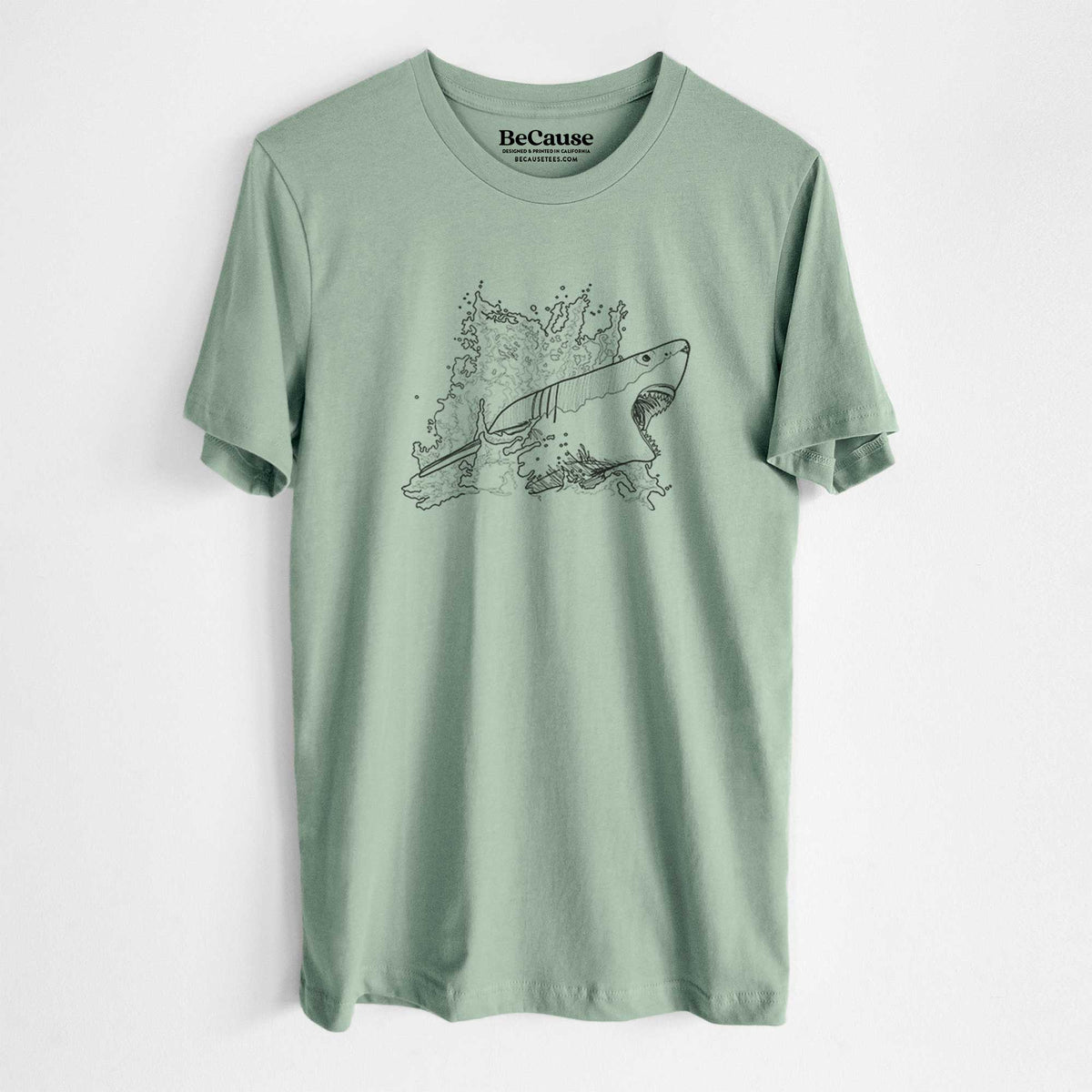 Sage green lightweight cotton t-shirt laid flat, printed with a black ink illustration of a great white shark breaking through a splash of water.