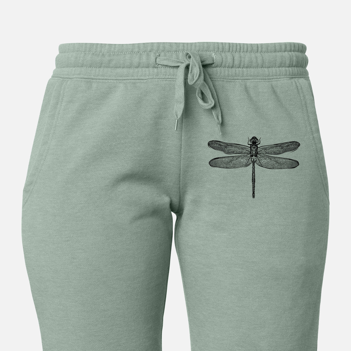 Front of sage green Cali Wave sweatpants, printed with a detailed black ink illustration of a green darner dragonfly with its wings spread, seen from above on the leg.