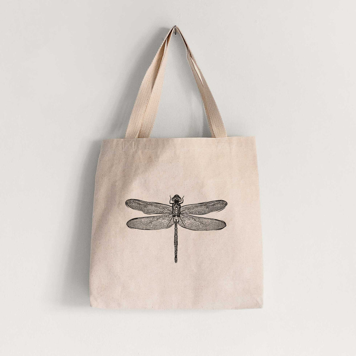 Natural canvas tote bag printed with a detailed black ink illustration of a green darner dragonfly with its wings spread, seen from above.