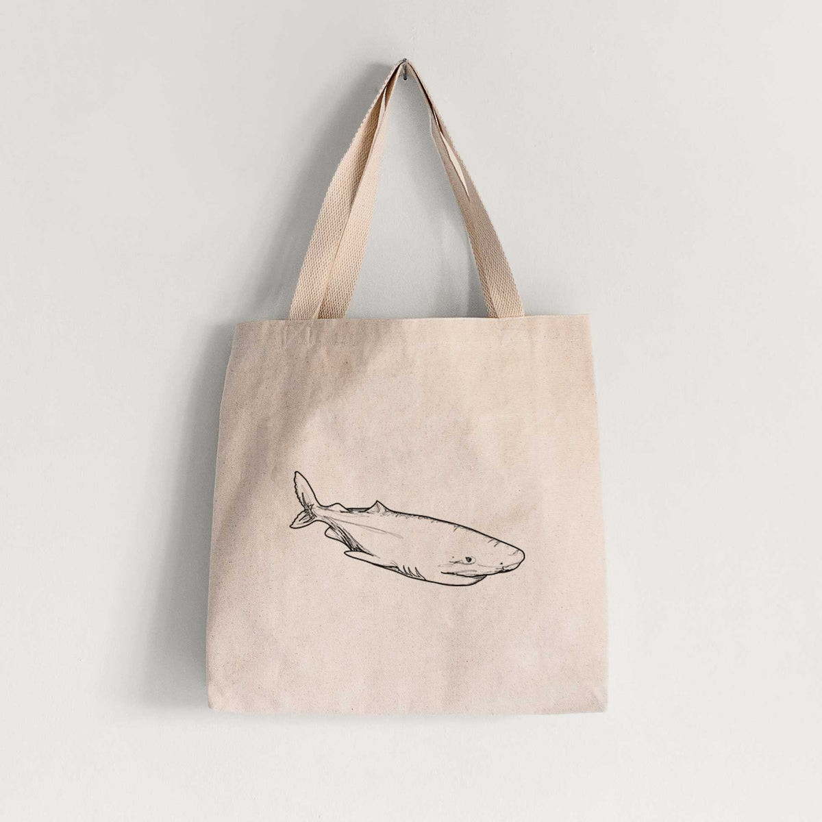 Natural canvas tote bag printed with a black ink illustration of a Greenland shark swimming.