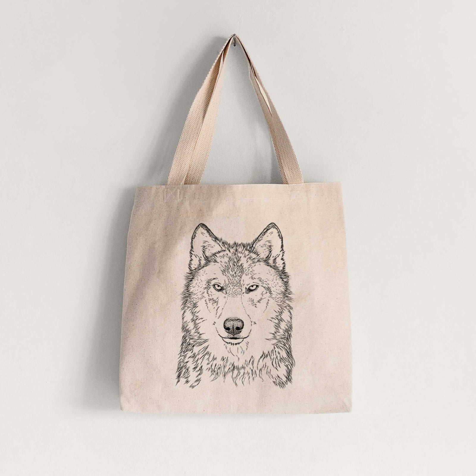 Natural canvas tote bag printed with a detailed black ink portrait of a grey wolf facing forward.